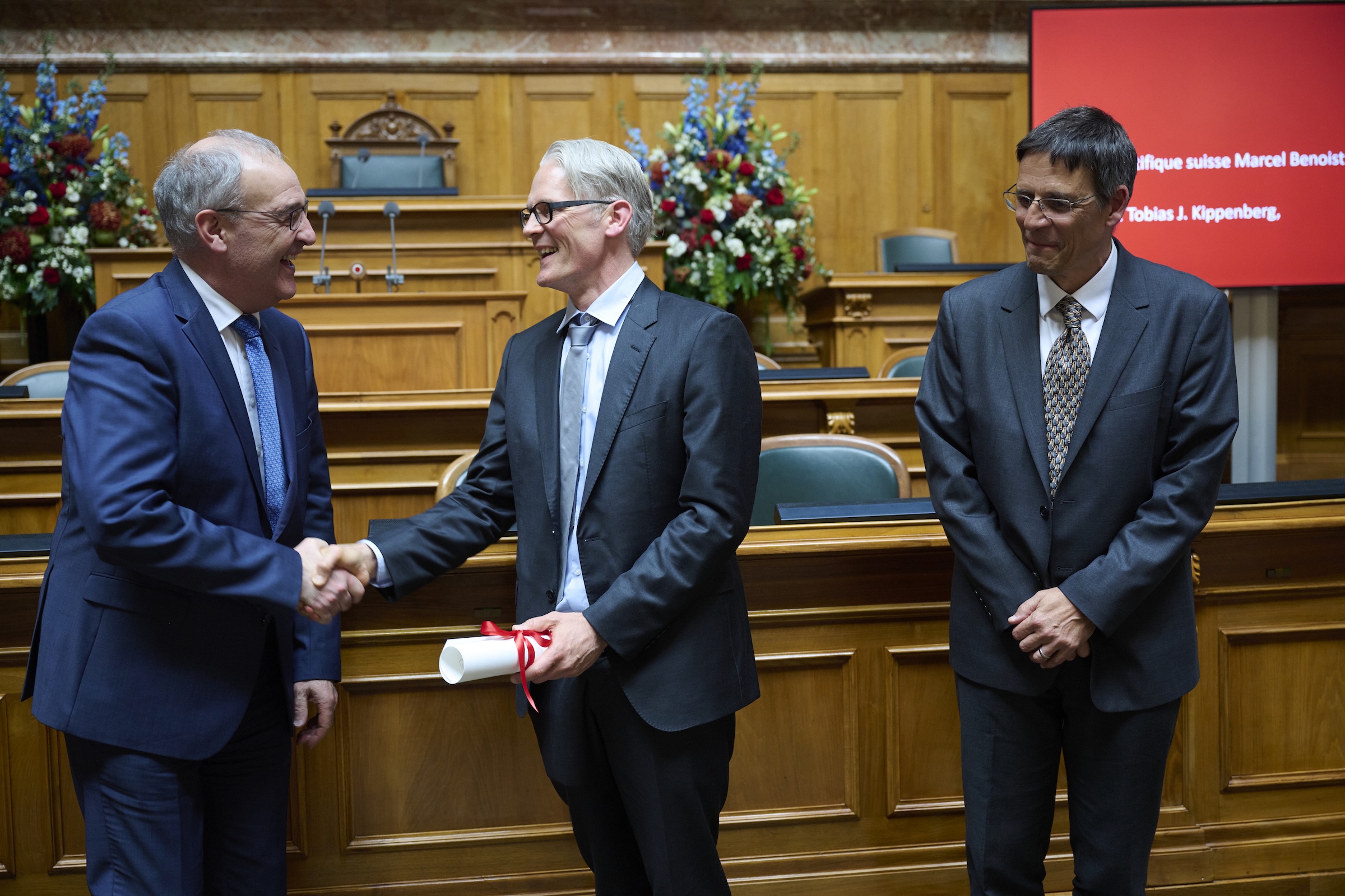 Le Conseiller Fédéral Guy Parmelin félicite Tobias Kippenberg qui reçoit le prix Scientifique Suisse Marcel Benoist 2025 de Didier Queloz, Président de la Fondation Marcel Benoist (Copyright: Franca Pedrazzetti)